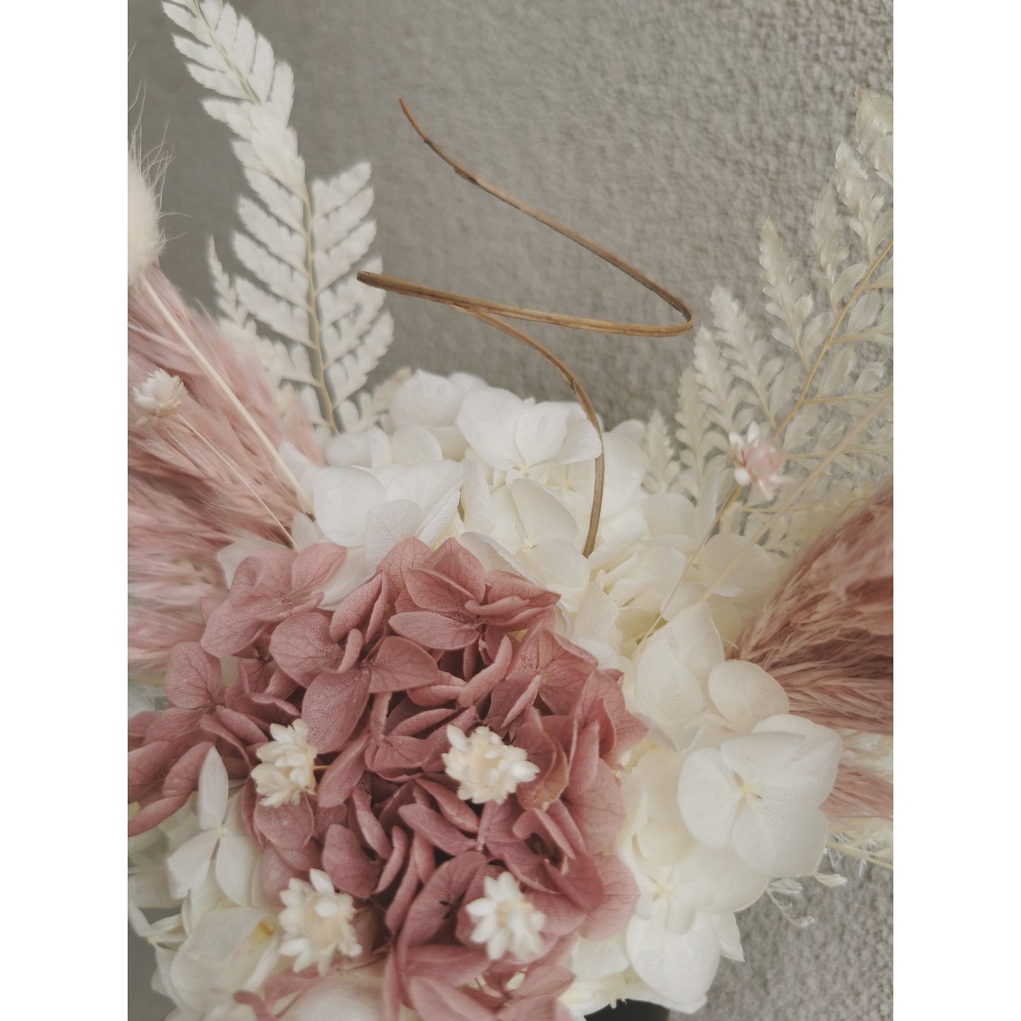 Dried & preserved flowers in dusy pink and white and designed to look like angel wings & halo and set in to a mini black pot. Picture shows flowers held against a blank wall and zoomed in to show a closer look at flowers