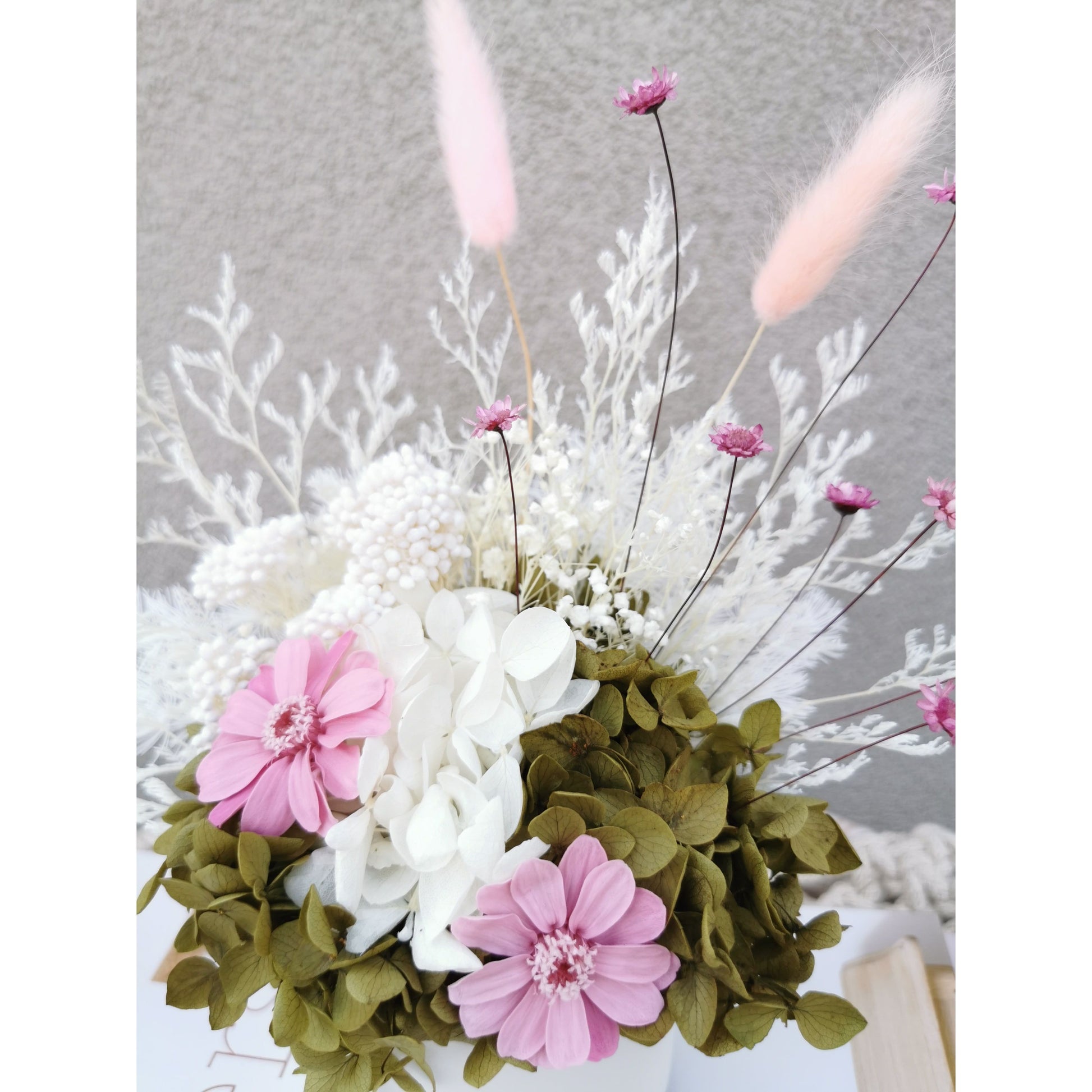 Dried & Preserved flower arrangement in pink, green & white featuring pink zinnia flowers. Photo shows a close up of the flowers
