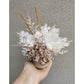 Neutral coloured dried & preserved flower arrangement. Photo shows arrangement being held by hand against a blank wall.