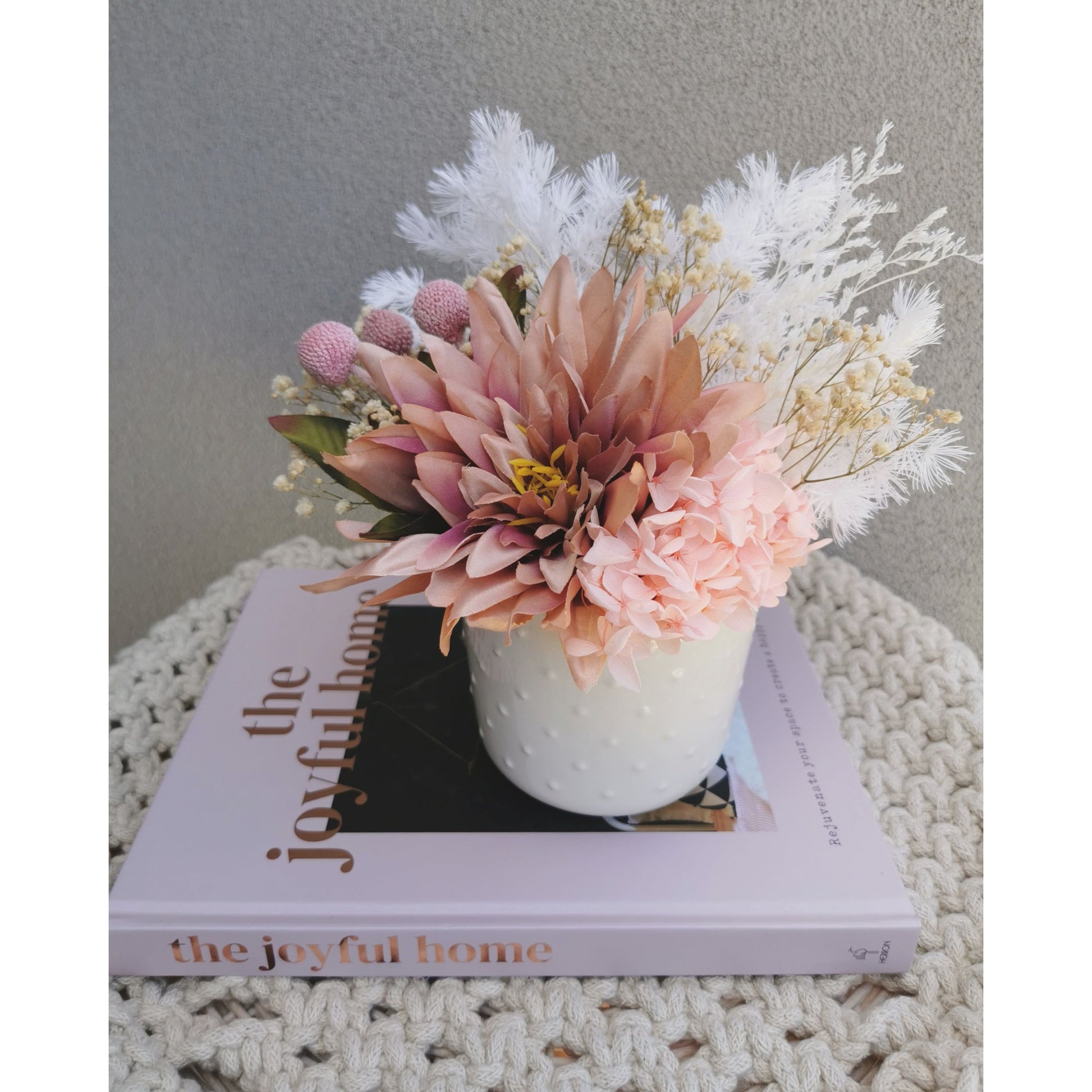 Dried & Preserved flower arrangement with silk artificial Dahlia flower. Photo shows arrangement sitting on a book against a blank wall