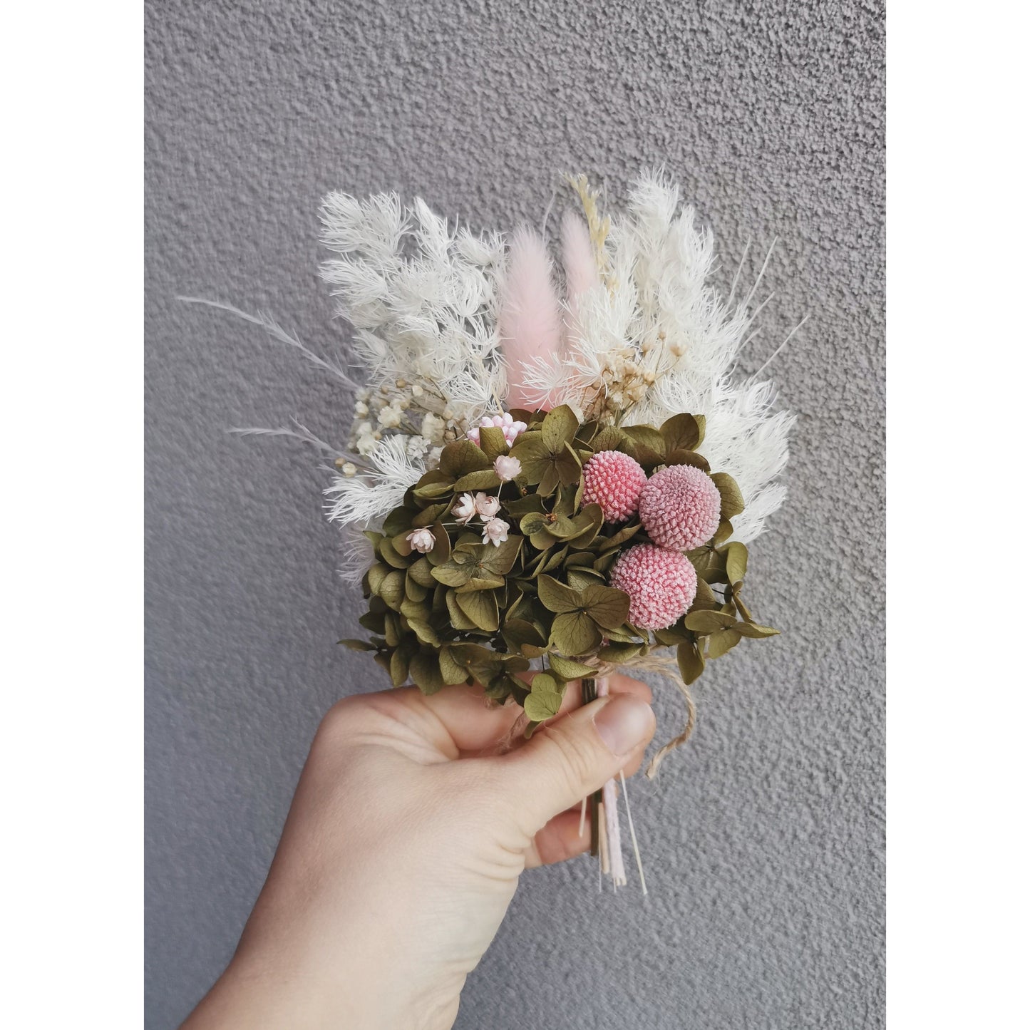 Gift Box Hamper with 2x soy wax melts, pink peony candle &  pink, green & white dried flower posy. Photo shows the dried flower posy being held by hand against a blank wall