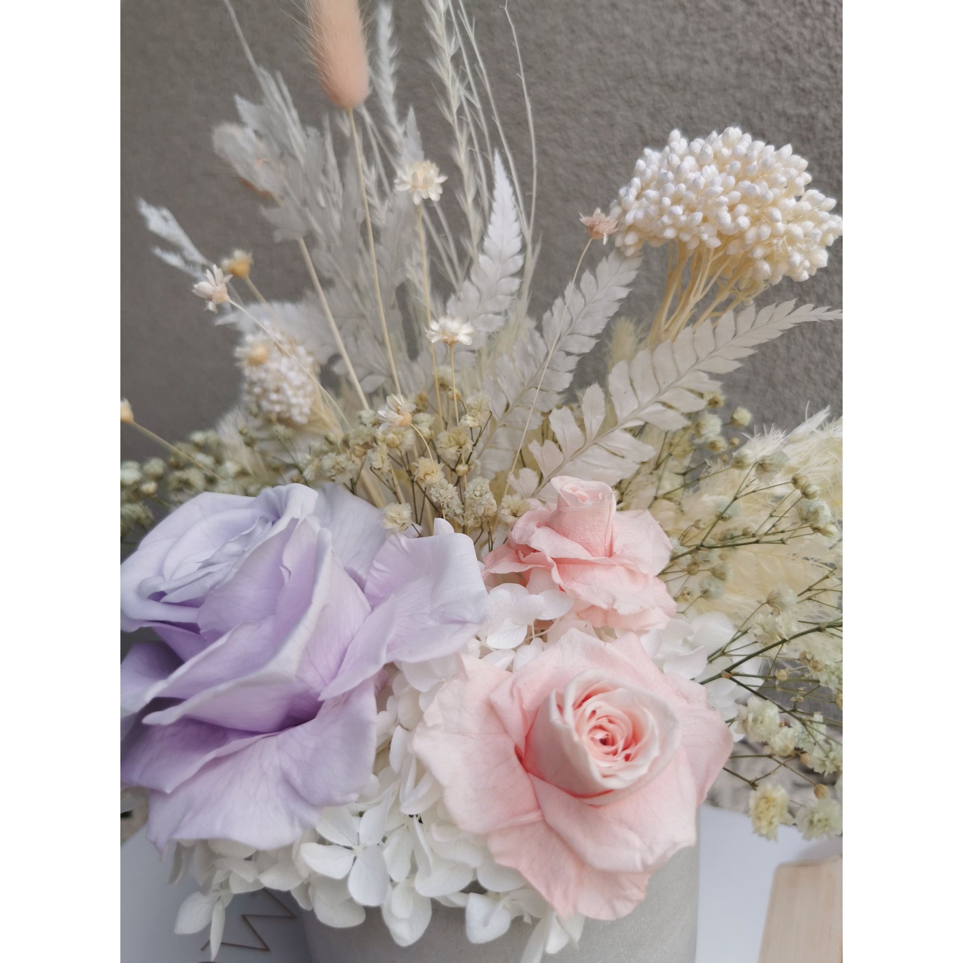 Dried & Preserved flower arrangement in pastel pink, purple & white flowers and set in to a light grey cement pot. Photo shows a close up look of the flowers