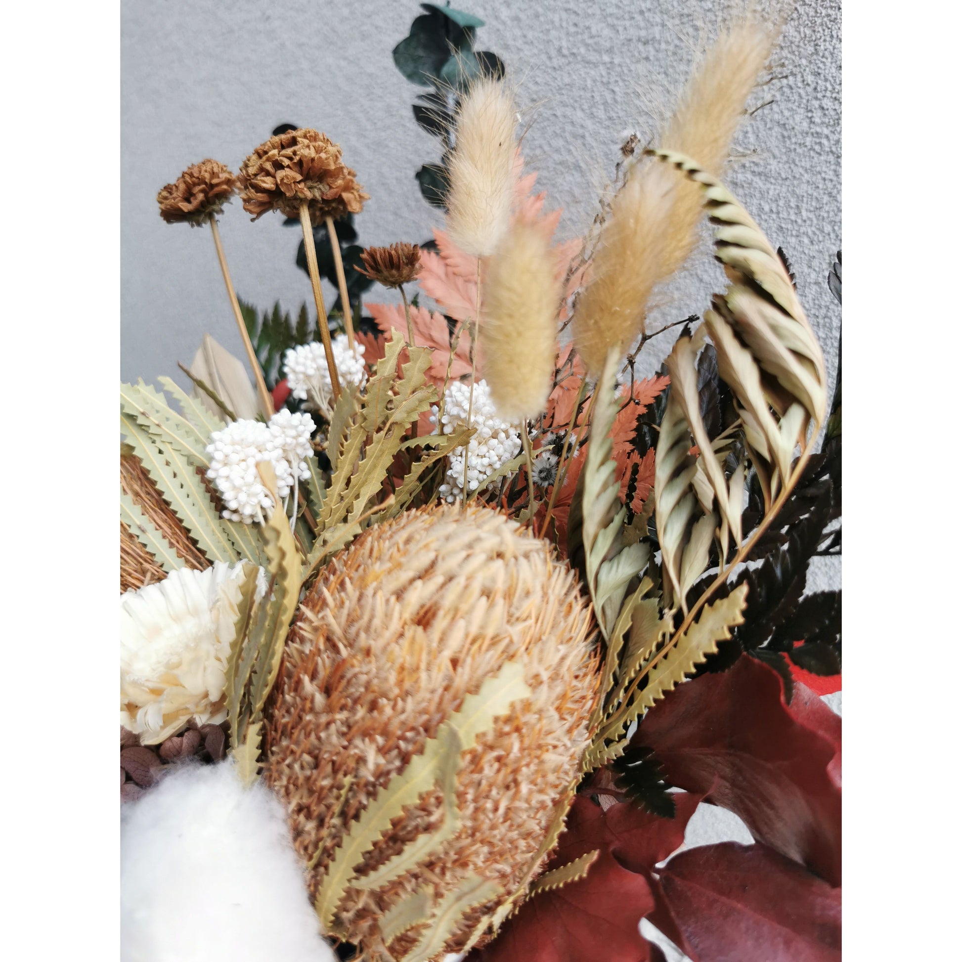 Dried & Preserved native flower arrangement in browns, greens, neutral colours and comes in a white pot including banksias, ferns & bunny tails to name a few. Photo shows a zoomed in close up of the flowers