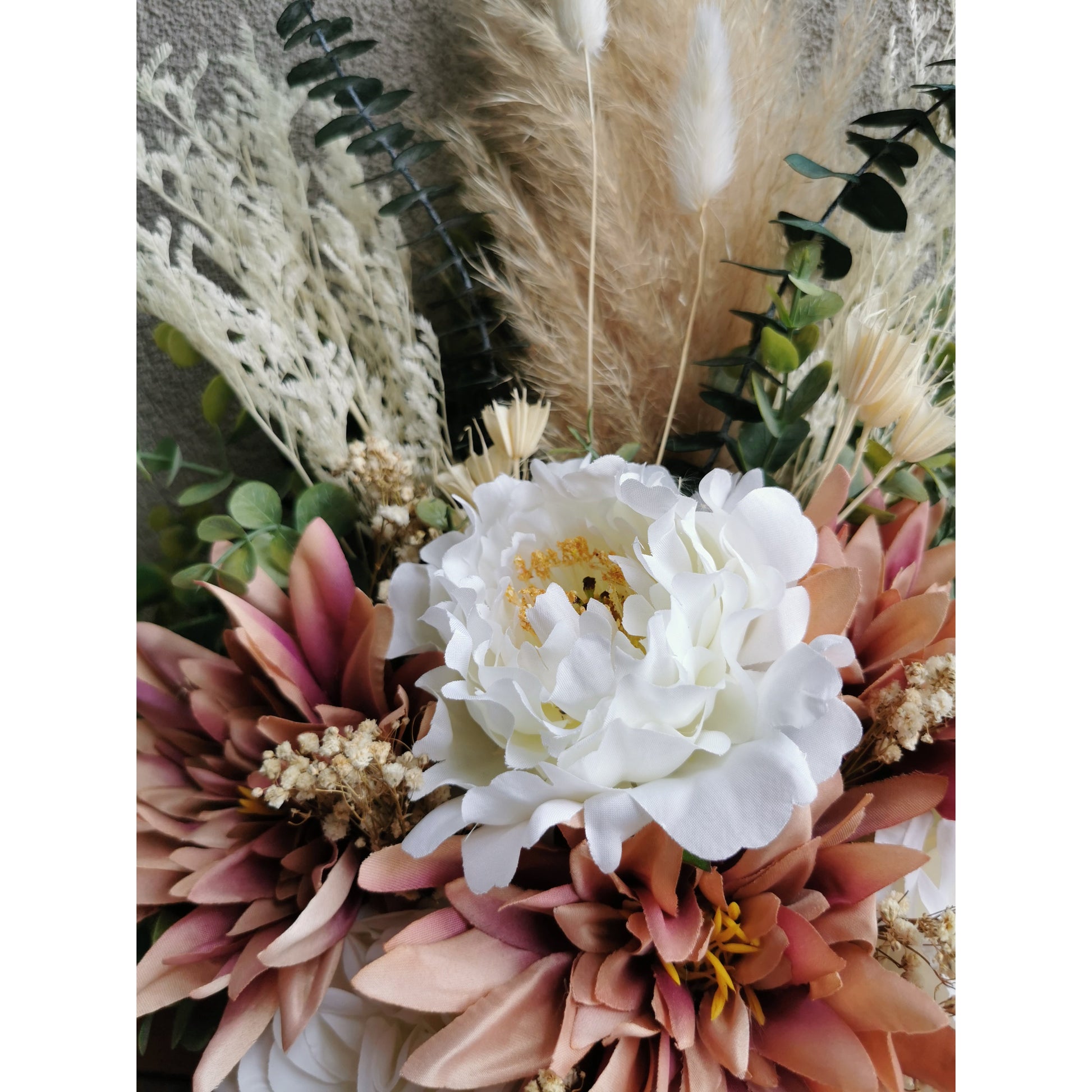 Close up photo of premium artificial flowers inc dahlias and roses and eucalyptus plus dried real pampas grass in pink ribbed pot